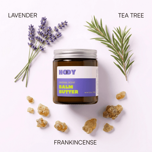 Jar of HODY Original Scent Balm Butter surrounded by its scent ingredients: lavender, tea tree and frankincense resin