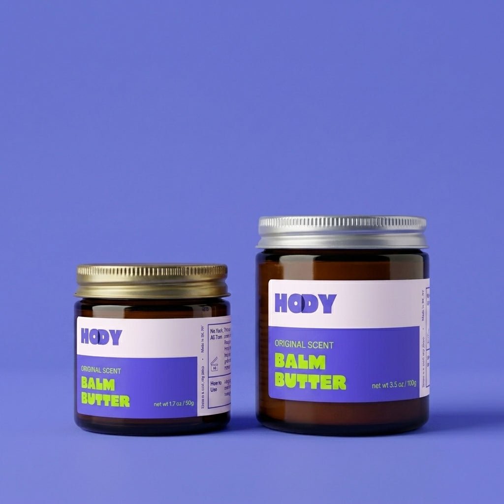 HODY Original Scent Balm Butter in small and large amber glass jars on a purple background